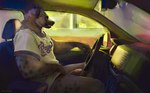 anthro black_body black_fur bottomless bottomless_anthro bottomless_male brown_body brown_fur car clothed clothing crucifix drive-thru driving fur genitals glans humanoid_genitalia humanoid_penis jewelry male markings multicolored_body multicolored_fur necklace pantsless penis pink_glans prank public public_nudity shirt shirt_only solo spots spotted_body spotted_fur t-shirt t-shirt_only topwear topwear_only two_tone_body two_tone_fur vehicle mokejumps hyena mammal spotted_hyena hi_res
