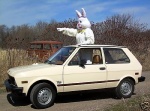 anthro car clothing costume female fursuit gesture hand_gesture holidays pointing real russia russian solo sunroof through_window vehicle what unknown_artist easter yugo_(automobile) easter_bunny lagomorph leporid mammal rabbit grandfathered_content low_res